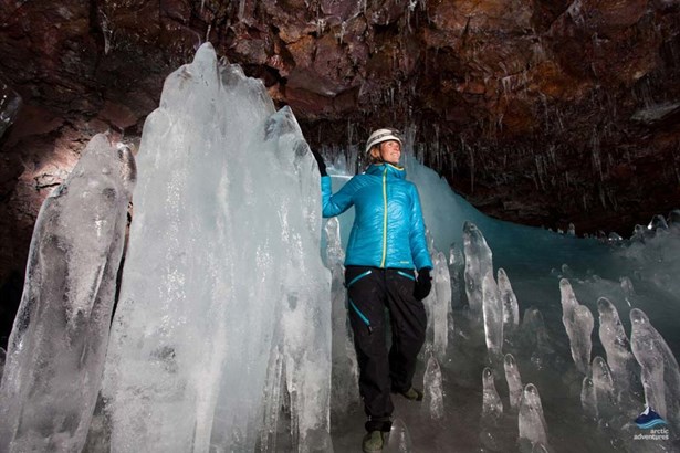 woman in lava cave by huge icicles