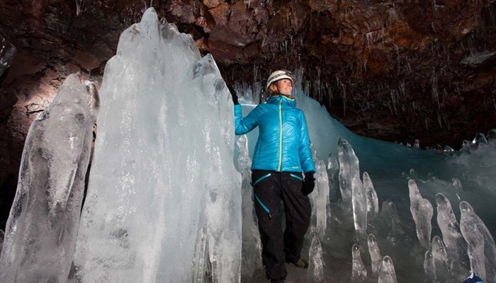 woman in lava cave by huge icicles