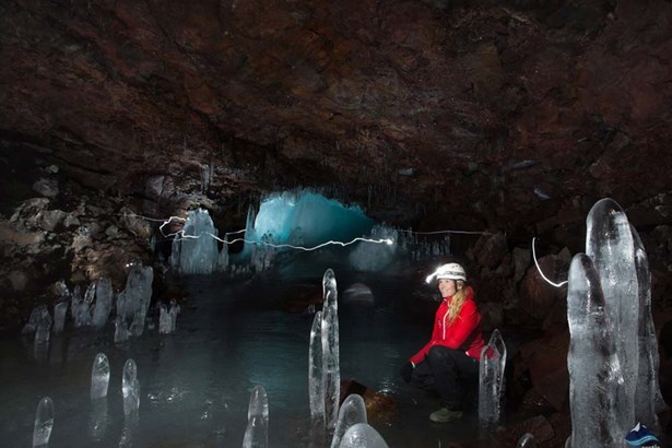 woman inside lava tube full of icicles
