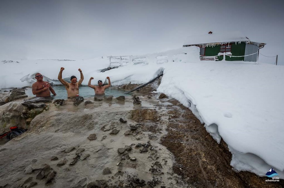 men bathe in hveravellir hot spring on winter