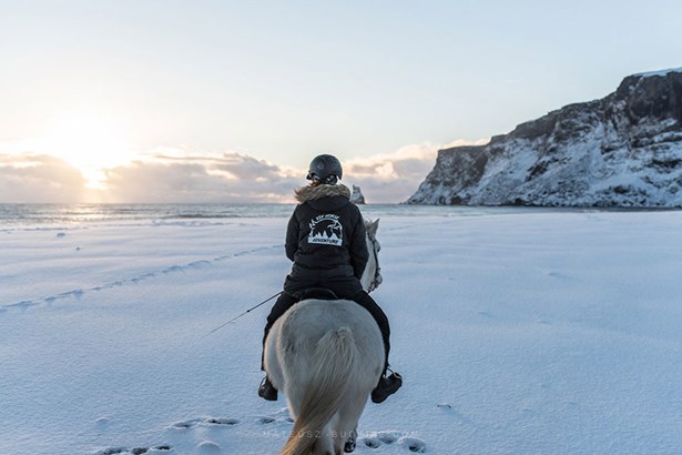woman riding horse at beach in winter