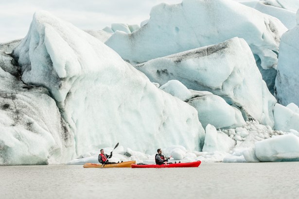 two men paddling near ice of glacier