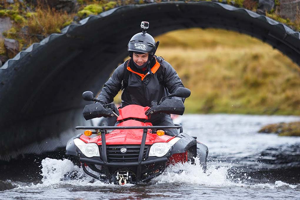 man crossing river with quad bike