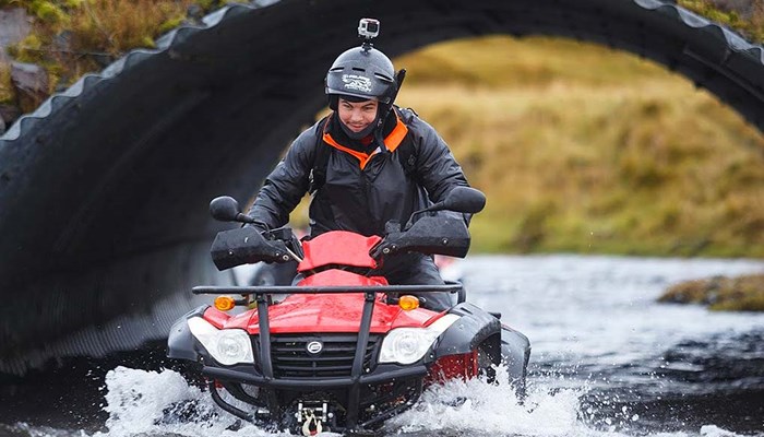 man crossing river with quad bike