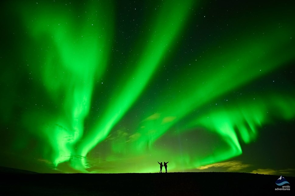 couple enjoying bright Northern Lights in Iceland