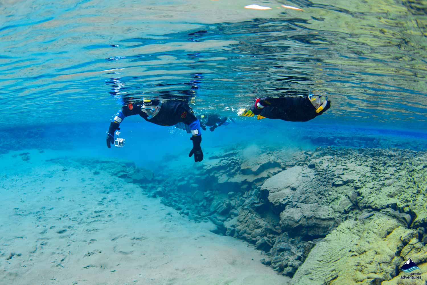 Two people swimming in crystal clear water in Silfra Fissure in Iceland.