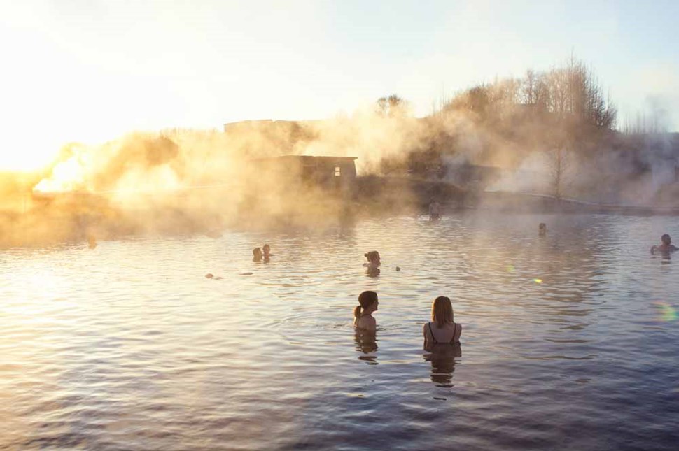 people bathe in steamy hot spring