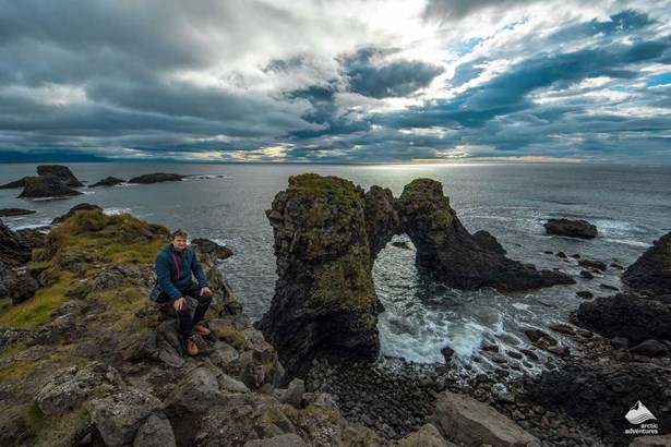 Man Sitting near Arnarstapi Cliffs in Iceland