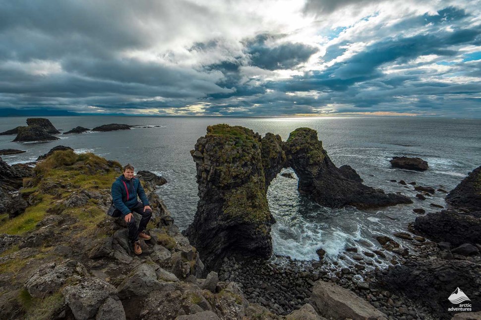 Man Sitting near Arnarstapi Cliffs in Iceland