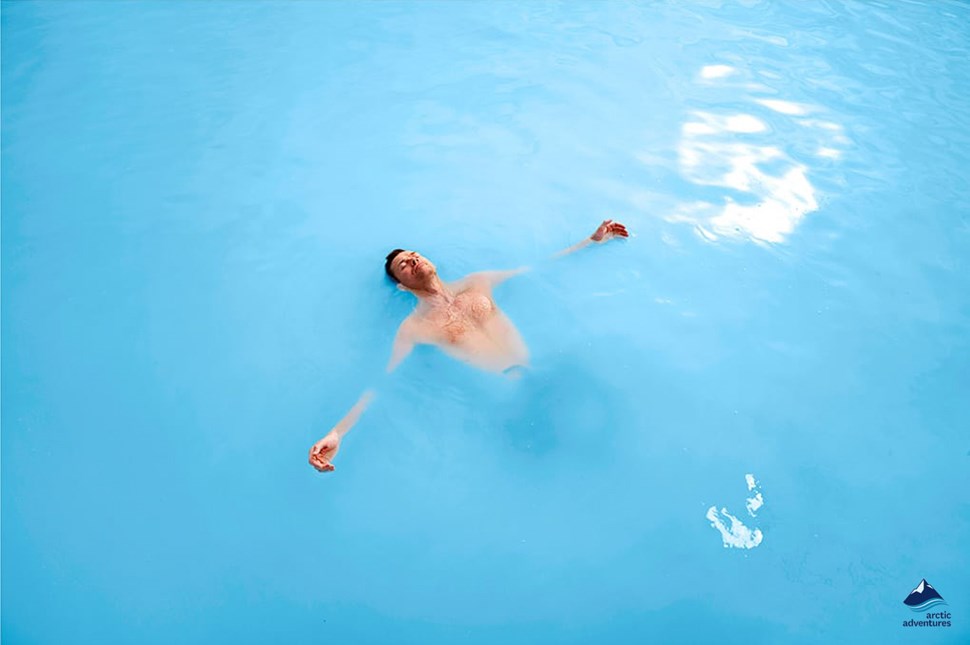 man swimming in iceland's blue lagoon
