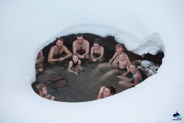 people bathe in hot spring covered in snow