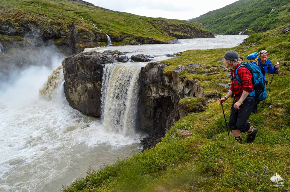 hikers trekking near waterfalls in Highlands of Iceland
