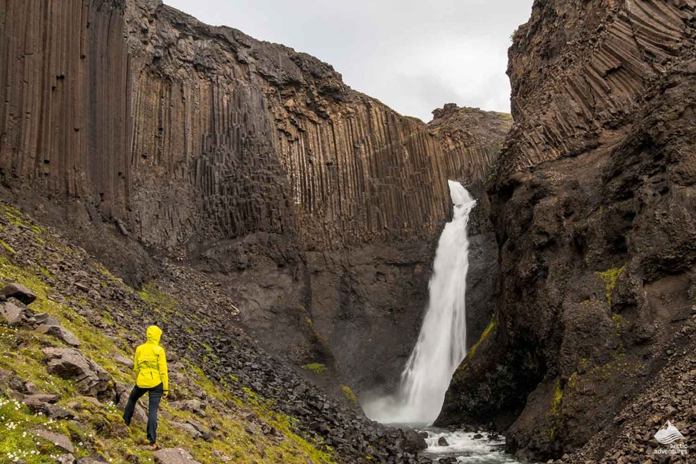 woman standing by Litlanesfoss waterfall