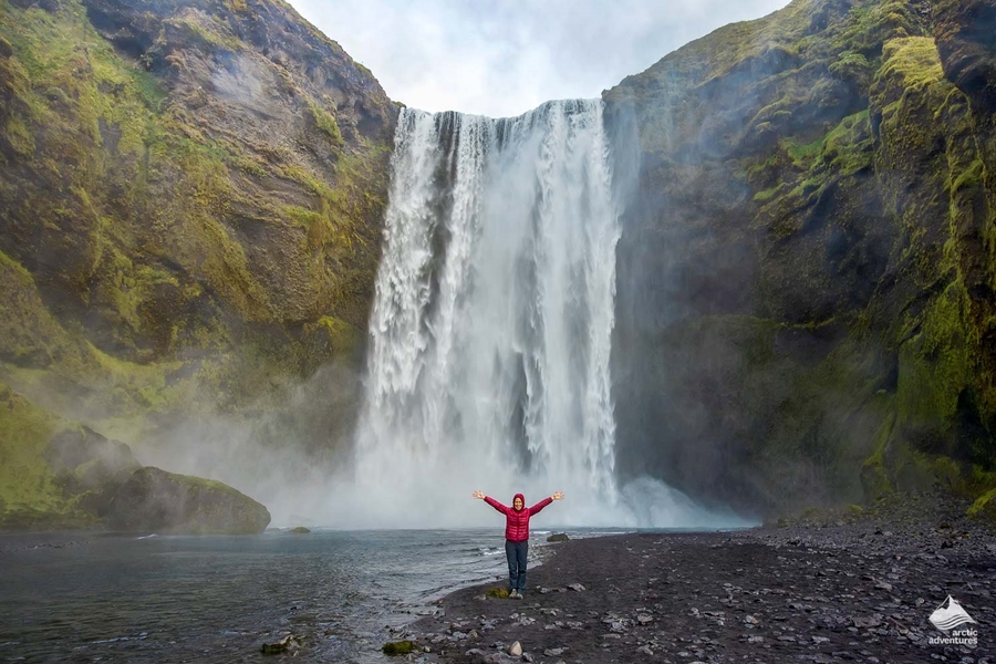Tourist standing under the giant Skogafoss Waterfall in Iceland
