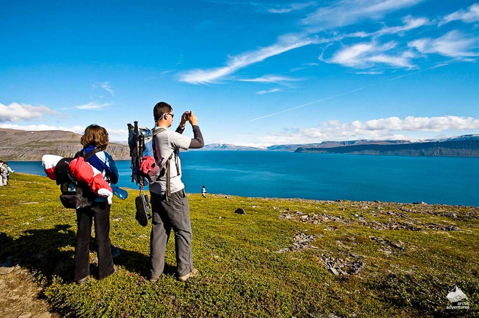hikers taking pictures of Hesteyri in Iceland