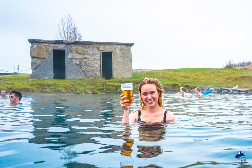 woman bathing and drinking beer in secret lagoon