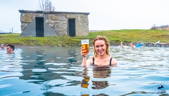woman bathing and drinking beer in secret lagoon