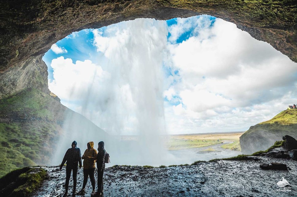 tourists standing behind Seljalandsfoss Waterfall