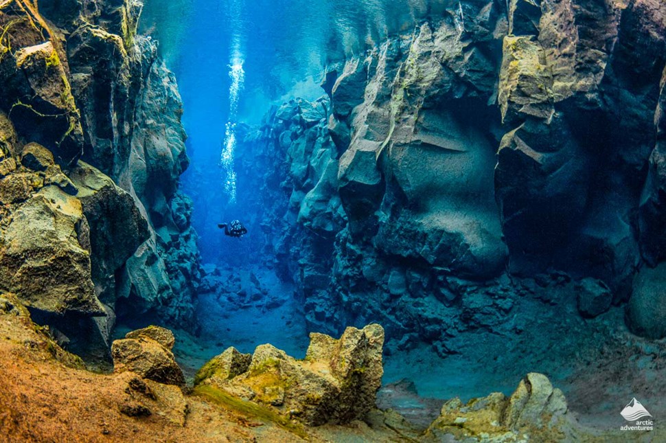 man diving between two continents at Silfra