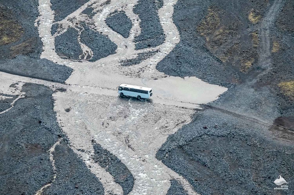 Large white coach driving through a rocky landscape