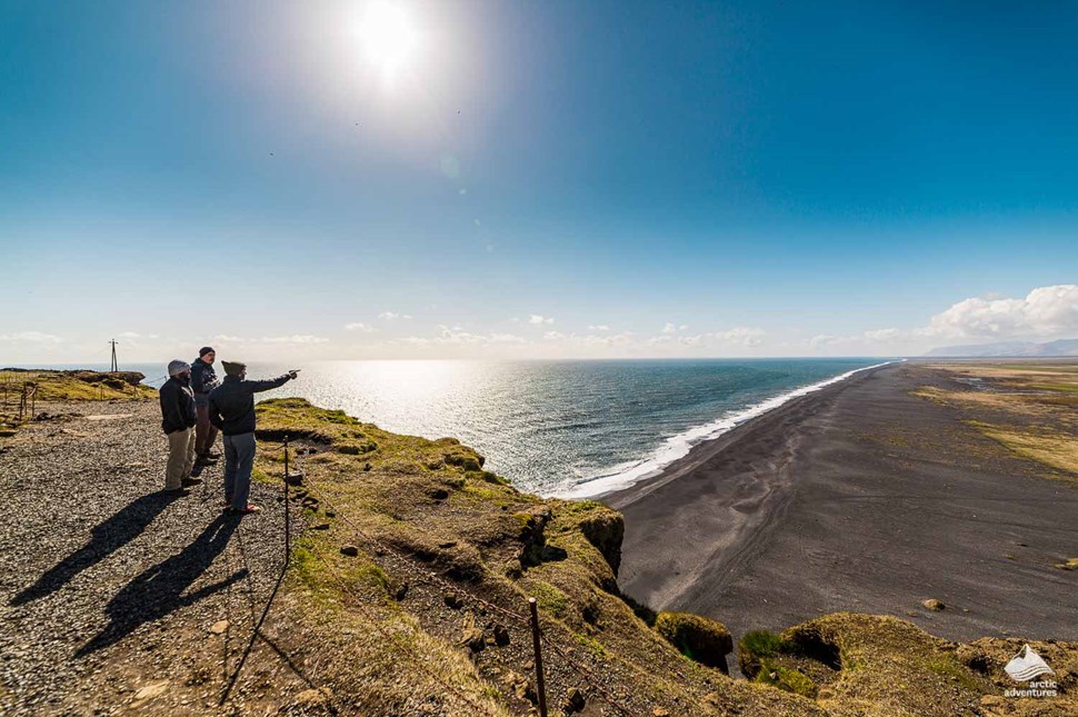Tourists looking at Black Sand Beach from the top