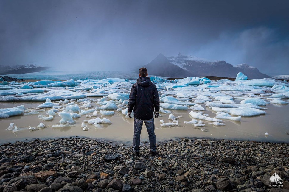 Man stands in front of Fjallsarlon Glacier Lagoon