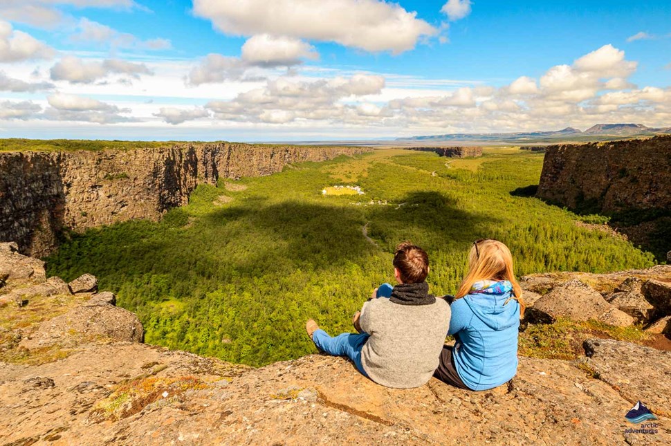 couple sitting on cliff in Asbyrgi canyon