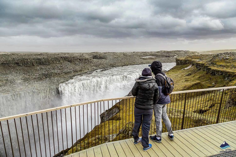 couple looking at Dettifoss Waterfall from viewpoint