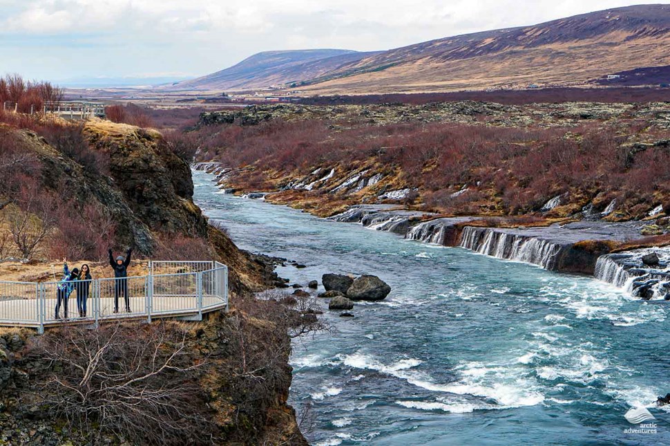 family standing at Viewpoint of Hraunfossar Waterfall