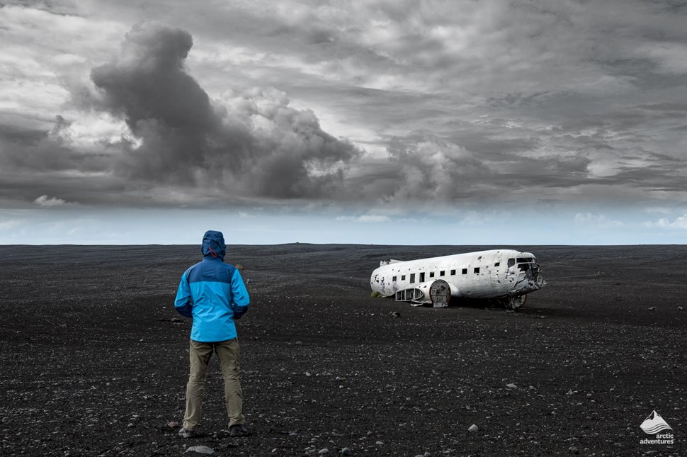 Man standing in front of plane wreck in Iceland