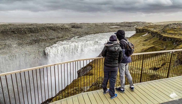 couple looking at Dettifoss waterfall from viewpoint