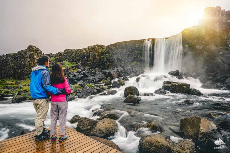 Couple looking at a small waterfall in Thingvellir National Park