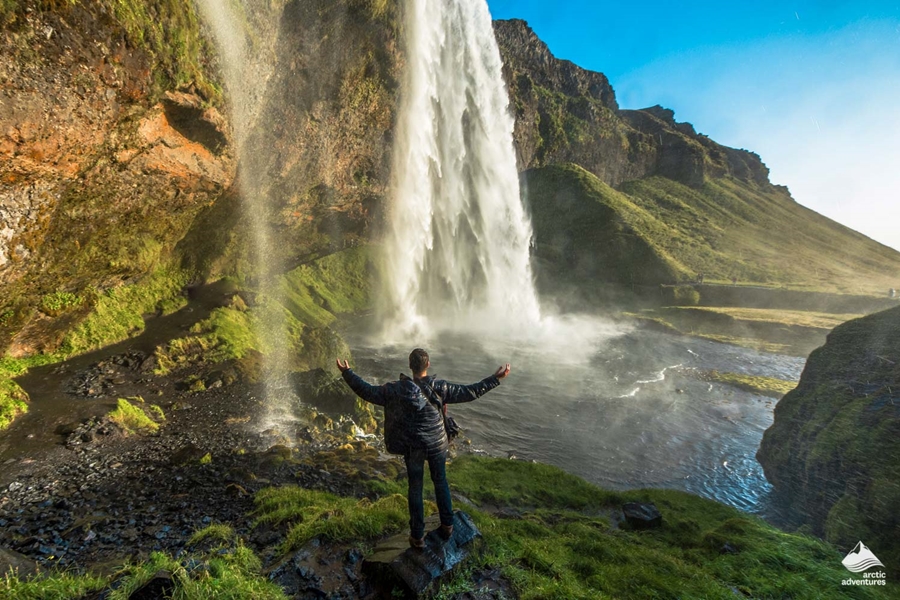 Tourist raised hands in front of Seljalandsfoss Waterfall