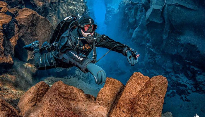 man diving by the lava cliffs in Iceland 