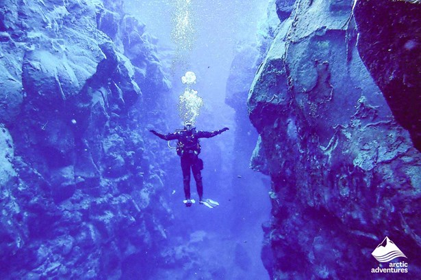 man Diving in blue water between cliffs