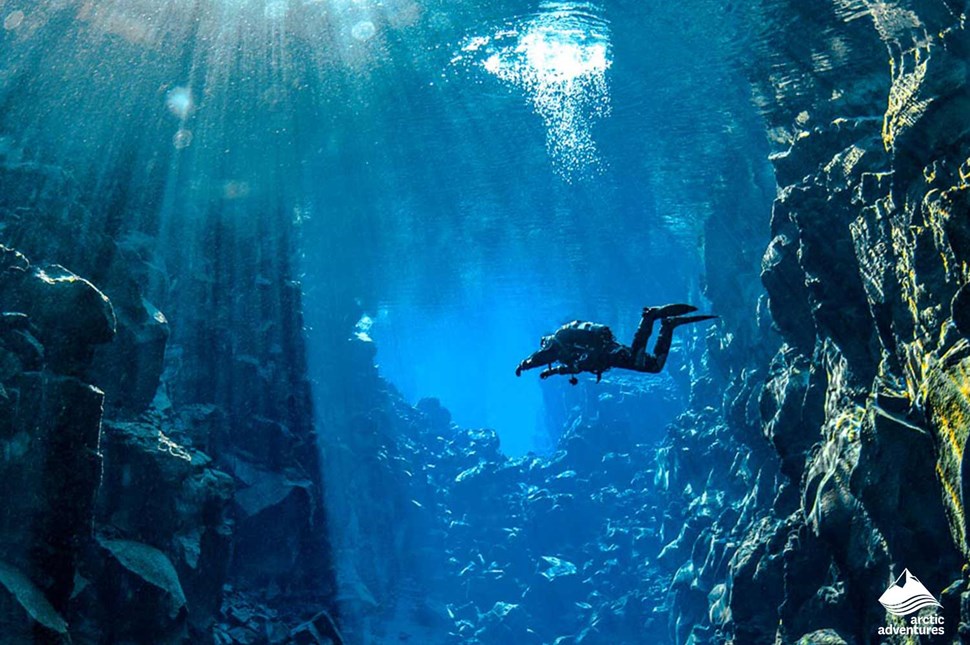 man Diving in bright blue water at Silfra