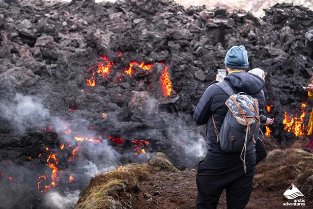 man taking pictures of hot volcano magma