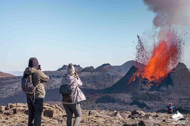explorers taking photographs of volcano eruption