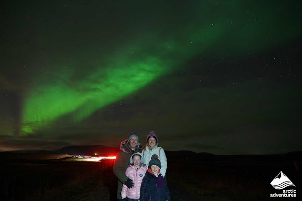 family taking picture under Aurora Borealis