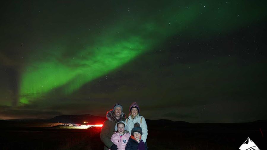 family posing under Aurora Borealis