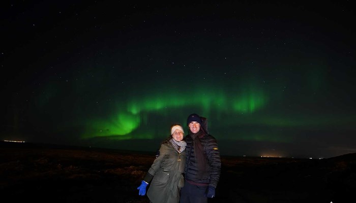 couple smiling under Northern Lights in Reykjavik