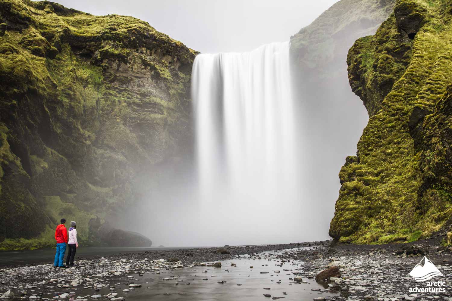 couple exploring Skógafoss waterfall in Iceland