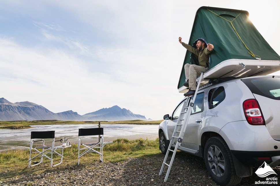 man camping in  Iceland inside car rooftop tent