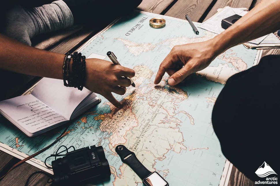 travelers planning trip and writing on map