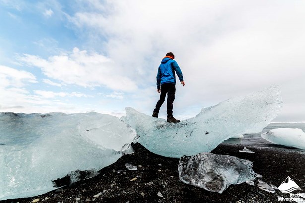 Man Standing on Huge Iceberg at Diamond Beach