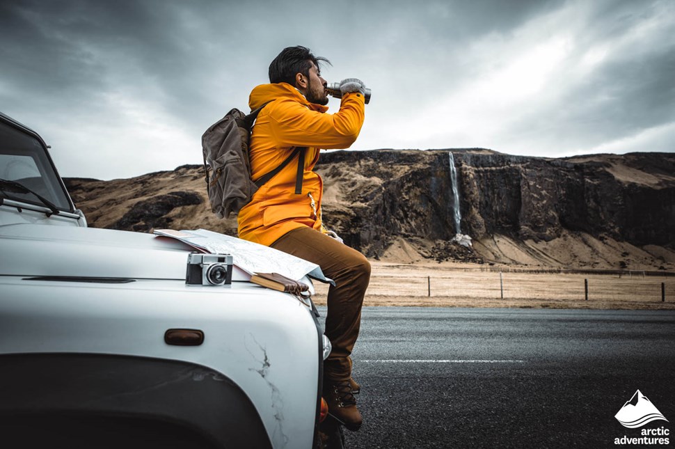 Traveler Sitting on Car and Drinking Water in Iceland