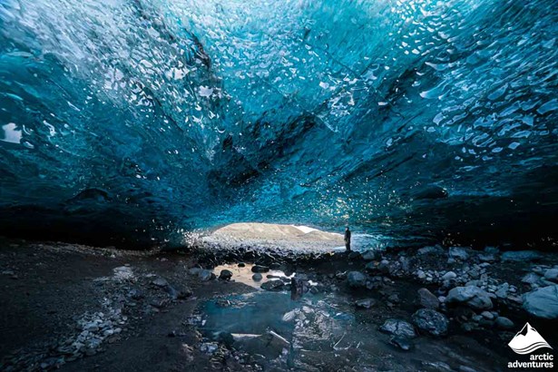 Man Standing Inside of Blue Ice Cave