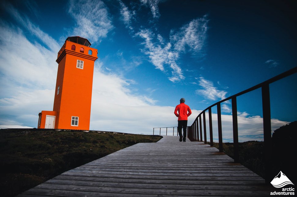 Man Walking Towards Svortuloft Lighthouse in Iceland
