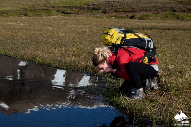 Woman Drinking Water from Pond in Iceland
