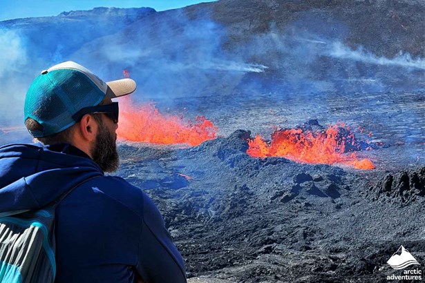 Man Standing by Erupting Volcano in Iceland